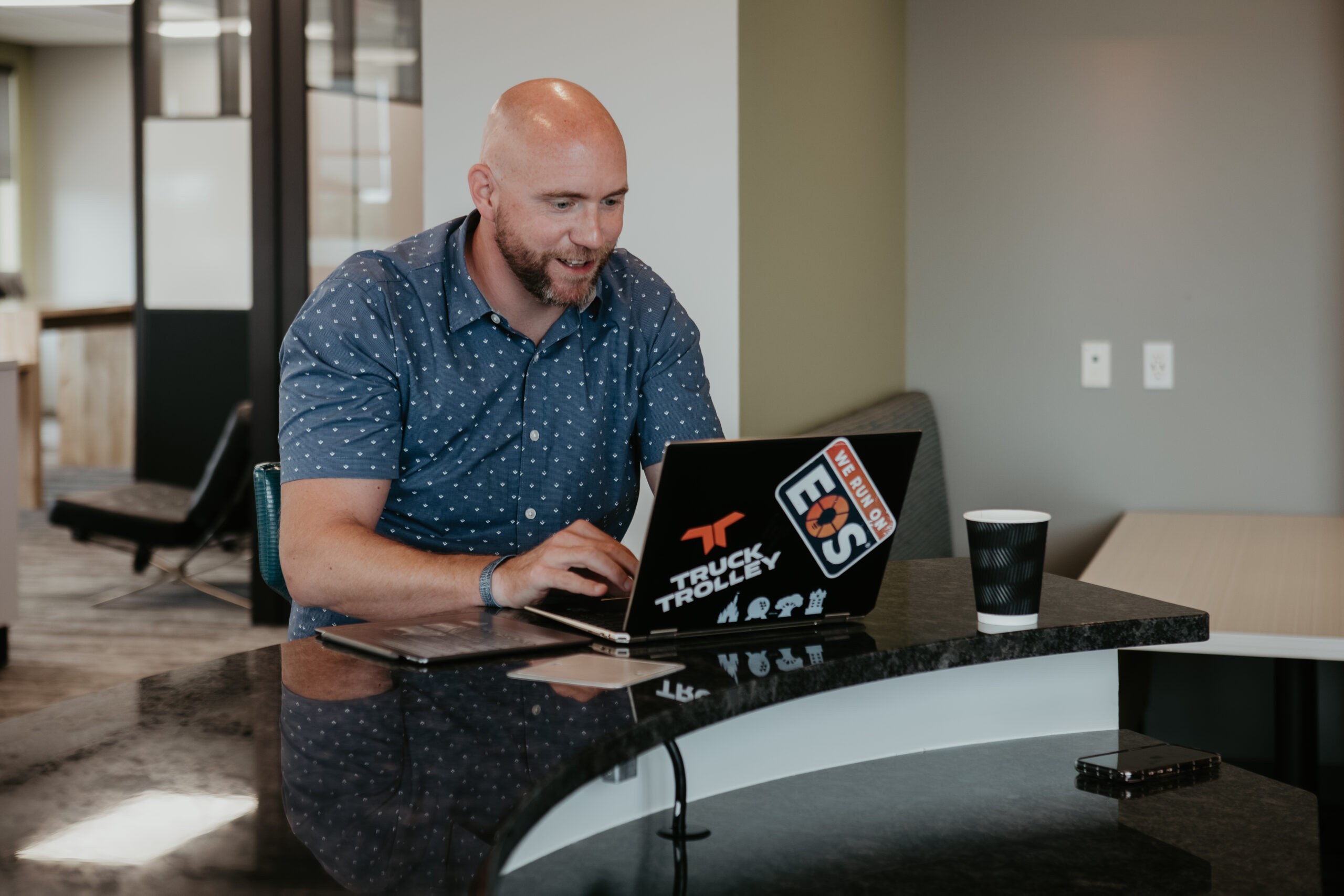 Andrew Wiess working on his laptop with EOS and Truck Trolley branding during a professional headshot and branding session in Bay City, Michigan.