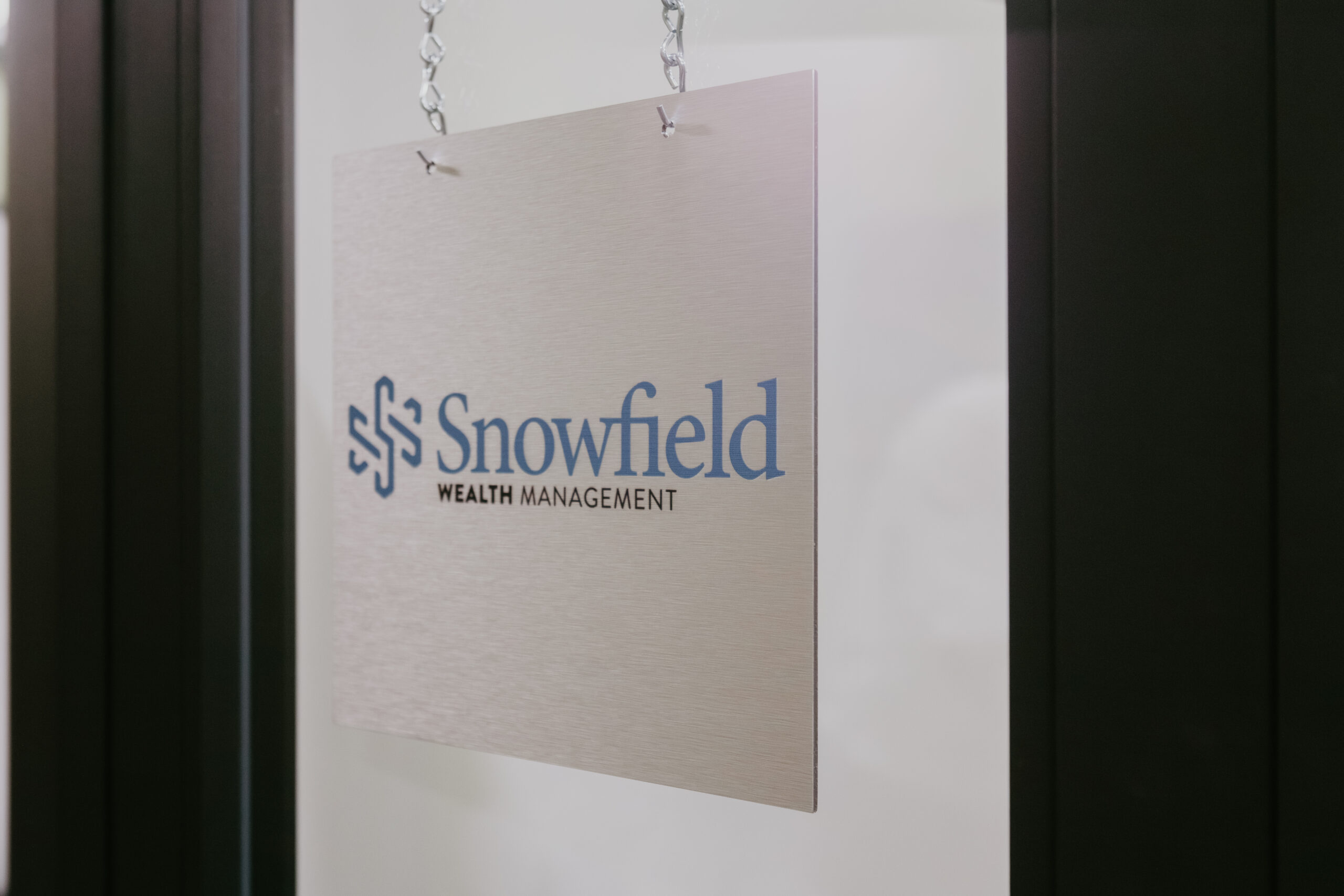 Snowfield Wealth Management office sign hanging at the Midland, Michigan location