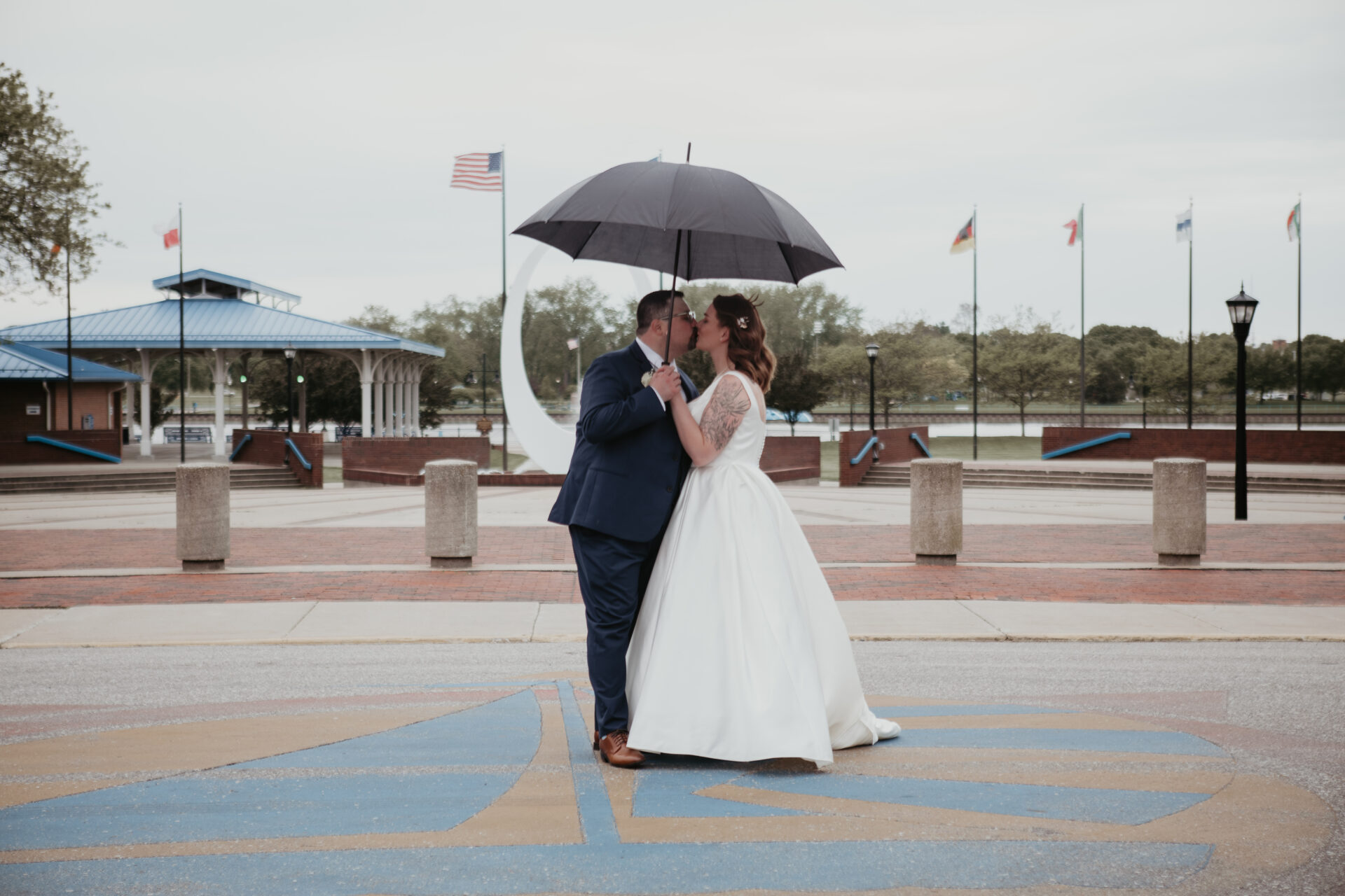 Bride and groom kissing under an umbrella in Wenonah Park, Downtown Bay City, Michigan during their wedding day