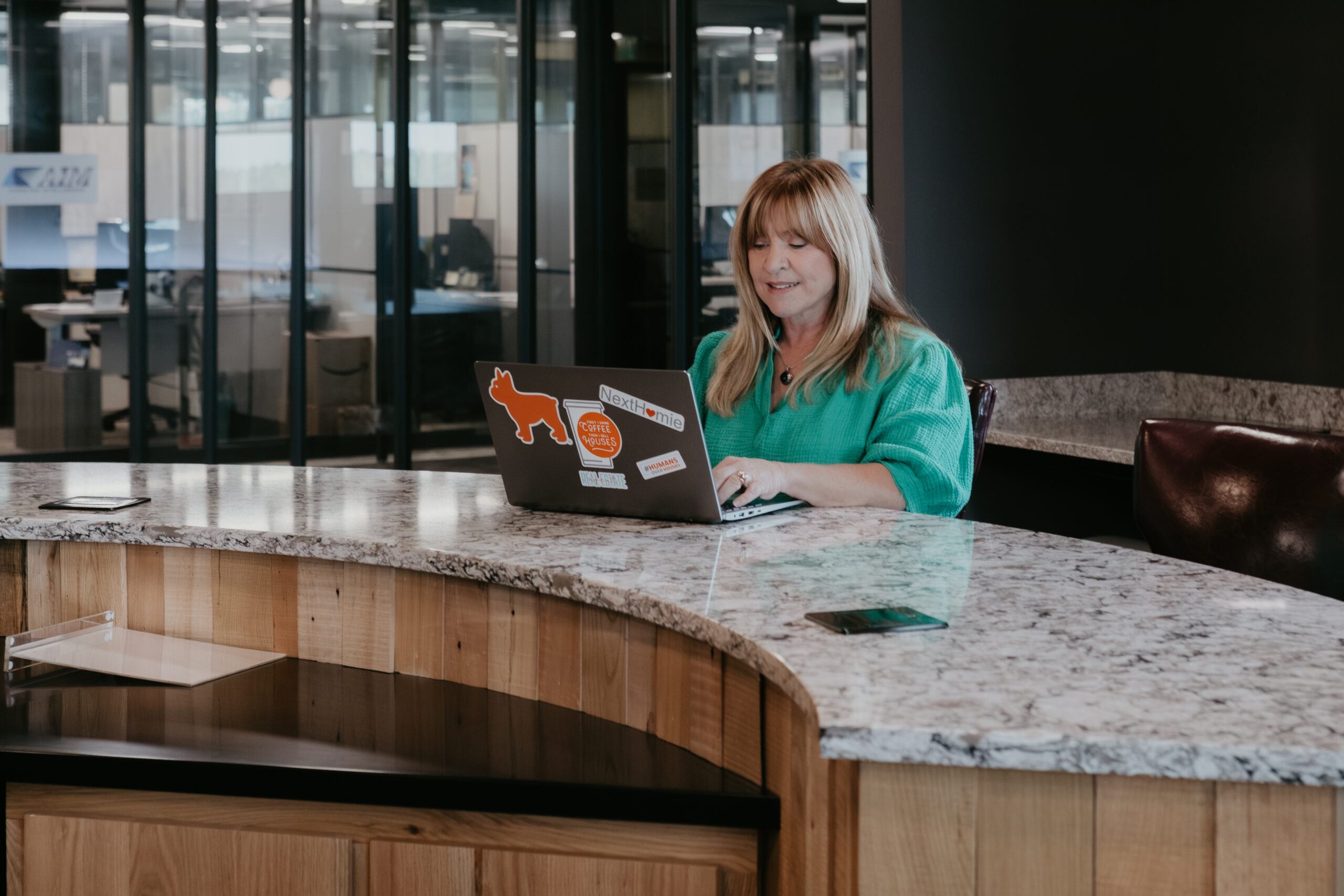 Shelley Park Cluff working on her laptop at a modern office in Midland, Michigan during a branding session with Arielle Roth Photography.