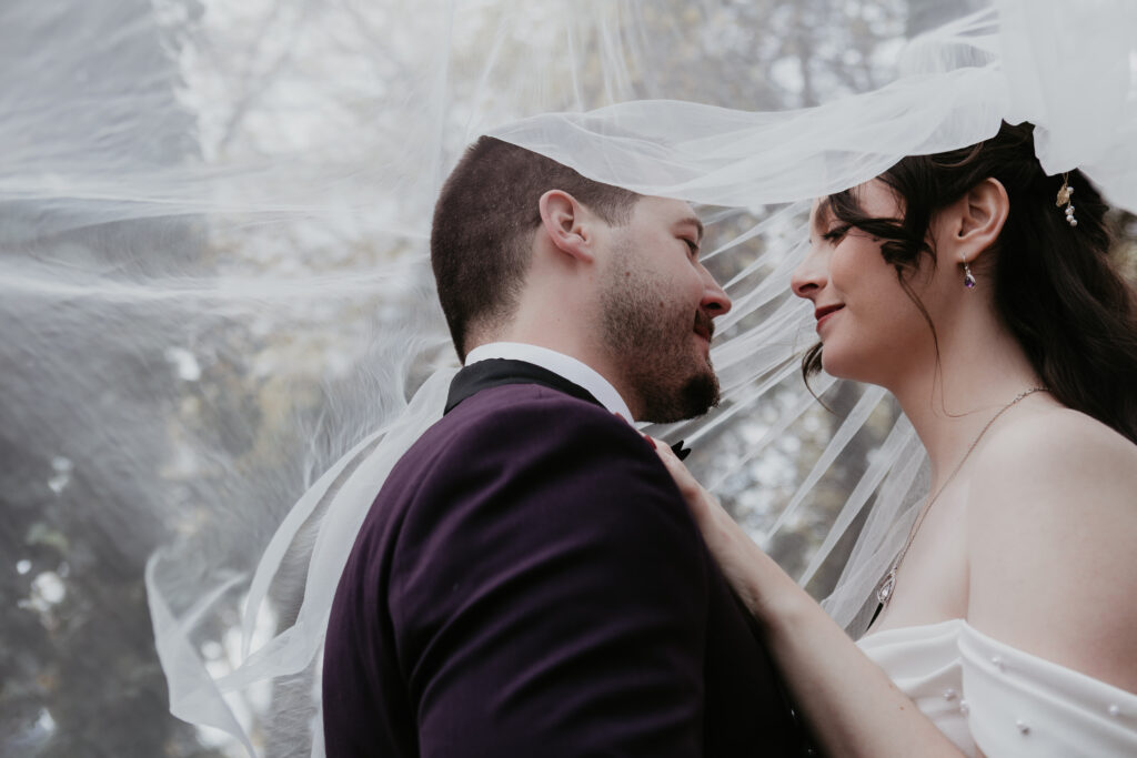 Bride and groom under flowing veil sharing an intimate moment during their wedding at Record Box Loft in Battle Creek, Michigan.